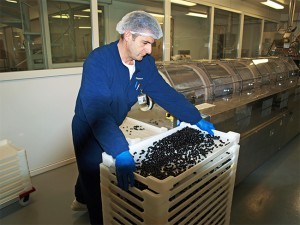 Man met grote plastic bakken, die geplaatst worden in een speciaal droogcompartiment